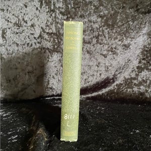 May include: A vintage book titled "Among My Books" by Lowell. The book has a light green cover with a floral pattern and the title in gold lettering. The spine also displays the number "8111" and the letter "L".
