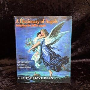 Może przedstawiać: Książka w twardej oprawie zatytułowana A Dictionary of Angels including the fallen angels autorstwa Gustava Davidsona. Okładka przedstawia niebieskawą ilustrację uskrzydlonej postaci niosącej dziecko, z nadrukowanym cytatem z The Times of London.