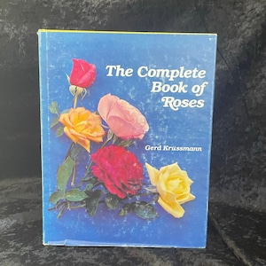 May include: A hardcover book titled "The Complete Book of Roses" with a blue cover. The cover features illustrations of various roses in shades of red, pink, and yellow. The author's name, Gerd Krüssmann, is printed below the title.