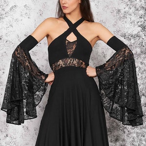 May include: A black dress with a lace overlay and long, flowing sleeves. The dress has a high neckline and a fitted bodice. The sleeves are made of sheer lace and have a bell shape. The dress is paired with black platform boots.