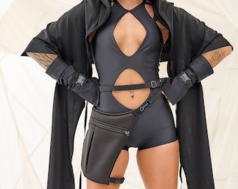 May include: A person wearing a black hooded top, black shorts, and black boots. The person is wearing sunglasses and has a black belt with a pouch attached.