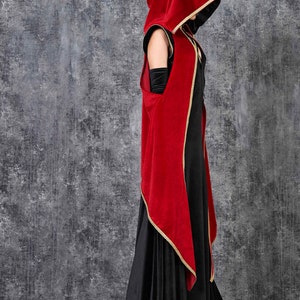May include: A long black dress with a red velvet hooded cloak. The cloak has gold trim and black lining. The outfit is a gothic style, suitable for cosplay or themed events. The dress is floor length.