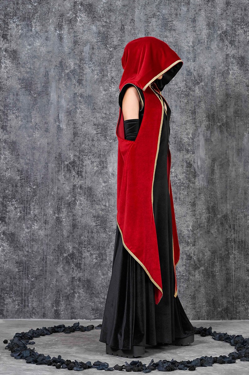 May include: A long black dress with a red velvet hooded cloak. The cloak has gold trim and black lining. The outfit is a gothic style, suitable for cosplay or themed events. The dress is floor length.