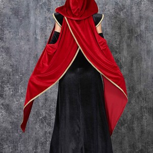 May include: A black velvet gown with a red velvet hooded cape, trimmed with gold. The cape is draped over the shoulders and arms. The costume is suitable for Halloween or cosplay events.