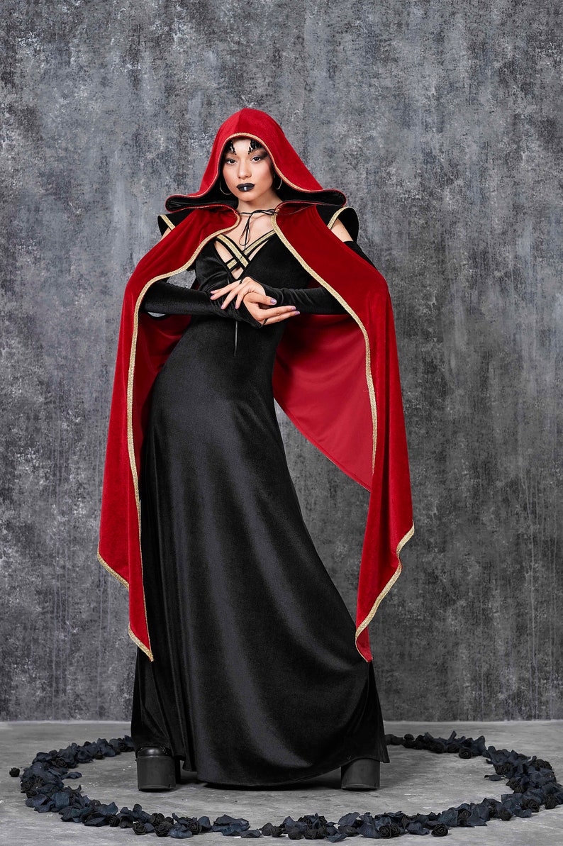 May include: A black velvet gown with long sleeves and a matching hooded cape. The cape is red with gold trim. The outfit is a gothic style, suitable for cosplay or themed events.