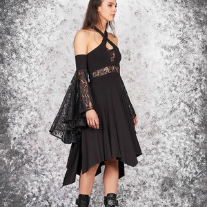 May include: A black dress with a lace overlay on the sleeves and a high neckline. The dress has a high-low hemline and is paired with black platform boots.
