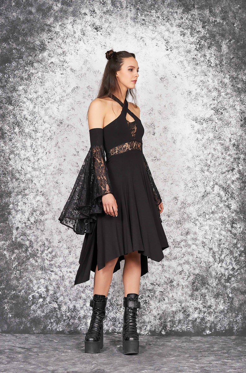 May include: A black dress with a lace overlay on the sleeves and a high neckline. The dress has a high-low hemline and is paired with black platform boots.