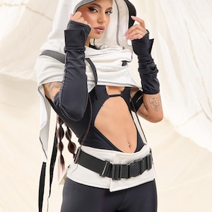 K&ouml;nnte beinhalten: Ein futuristisch anmutendes Outfit in Schwarz und Wei&szlig;. Das Ensemble umfasst ein Kapuzentop, lange Handschuhe, einen Body mit Ausschnitten und Leggings. Ein breiter G&uuml;rtel mit Schnalle betont die Taille. Das Outfit hat eine moderne, kantige &Auml;sthetik.