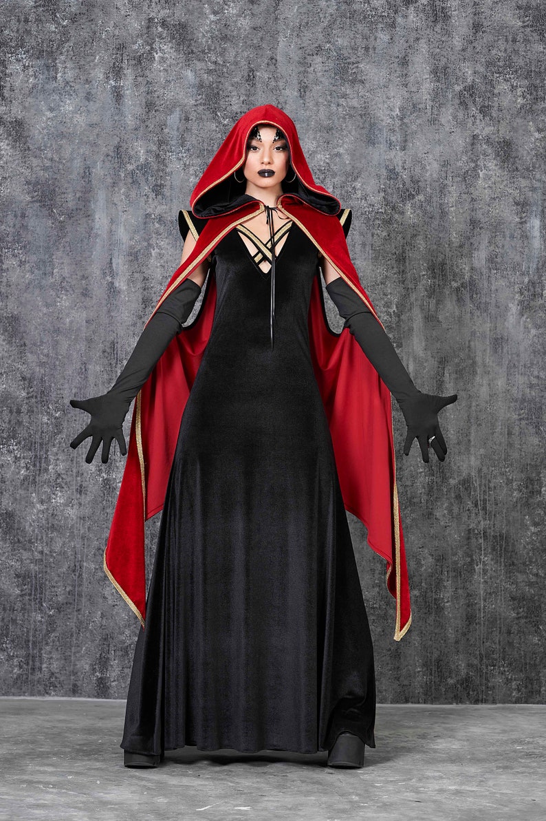 May include: A black velvet dress with a plunging neckline and a red hooded cape with gold trim. The long black gloves and dramatic makeup complete the gothic ensemble, perfect for a costume or themed event.