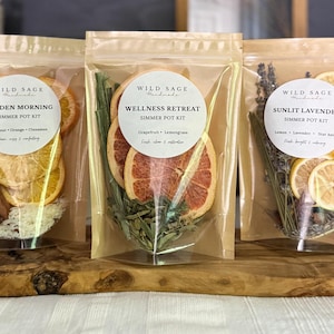 May include: Three clear stand-up pouches containing dried fruit and botanical simmer pot kits. Labels read Wild Sage Handmade, Golden Morning, Wellness Retreat, and Sunlit Lavender, listing ingredients like orange, grapefruit, lemon, and lavender.