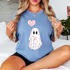 May include: A light blue t-shirt with a ghost holding a pink heart balloon that says "Be My Boo". The ghost is covered in pink hearts.