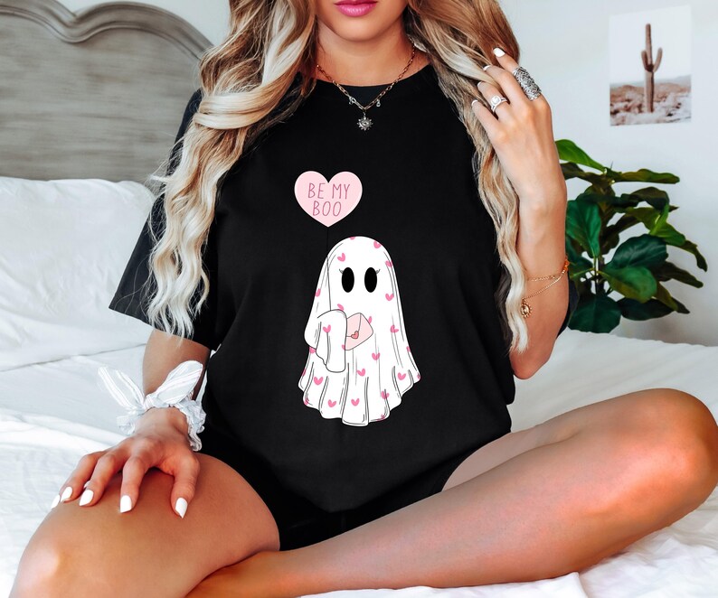 May include: Black t-shirt with a pink heart that says "Be My Boo" and a ghost holding a pink heart with a pink heart pattern.