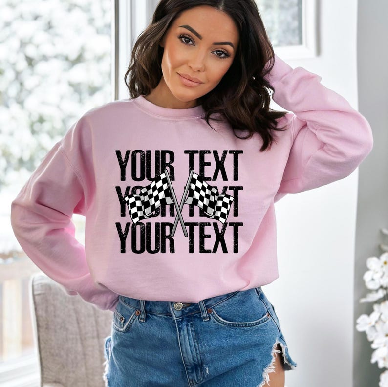 May include: Pink sweatshirt with a checkered flag graphic and the text "YOUR TEXT" repeated three times.