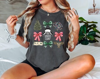 May include: A dark gray t-shirt with a Christmas theme featuring a Christmas tree, bows, lights, a camper, a moose, and the text "You Serious Clark?"