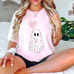 May include: Pink t-shirt with a ghost holding a heart-shaped balloon that says "Be My Boo".