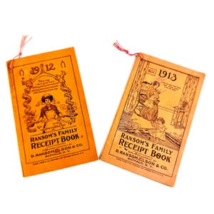 May include: Two vintage "Ransom's Family Receipt Book" booklets. The booklets are orange with black text and illustrations. One booklet is dated 1912 and the other 1913. Both have a red string attached at the top.