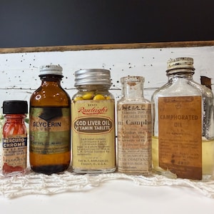 May include: A collection of vintage medicine bottles of various sizes and shapes. The bottles are labeled with names like "Glycerin," "Cod Liver Oil," and "Camphorated Oil." Some bottles have metal caps, while others have cork stoppers. The labels are aged and faded.