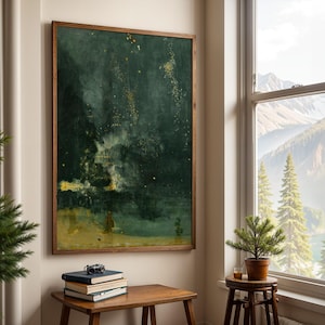 Pode incluir: Uma pintura abstrata emoldurada, com tons de verde escuro e dourado, pendurada em uma parede bege. A obra de arte está acima de uma pequena mesa de madeira com livros e uma câmera. À direita da pintura, há uma janela com vista para a montanha.