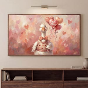 Könnte beinhalten: Gerahmtes Kunstwerk mit einer Gans, die einen Pullover und eine Fliege trägt und herzförmige Luftballons mit der Aufschrift "Be Mine" hält. Der Hintergrund ist rosa mit Herzen, was eine romantische und skurrile Szene schafft.