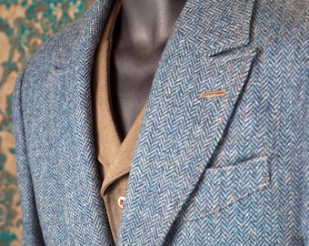 Puede incluir: Chaqueta de tweed azul con diseño de espiga, solapas con muescas y diseño de un solo pecho. La chaqueta presenta un bolsillo en el pecho y cierre de dos botones. Se ve una camisa marrón debajo.