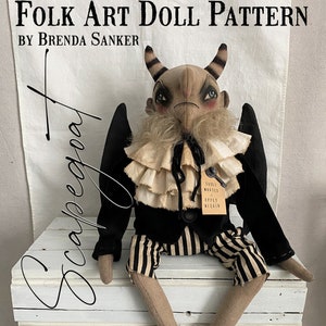 May include: A folk art doll pattern by Brenda Sanker featuring a whimsical, black-clad creature with horns, wings, and striped trousers. The doll is sitting on a white wooden crate. The text "Souls Wanted Apply Within" is on a tag attached to the doll.