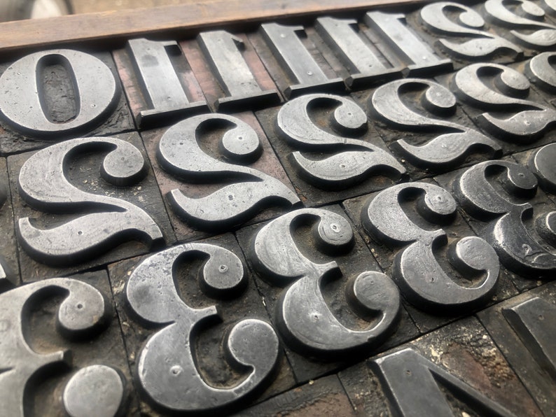 May include: Close-up of a collection of vintage metal letterpress printing blocks, featuring the numbers 0, 1, 2, and 3. The blocks are arranged in a grid pattern and show signs of wear and tear from years of use.