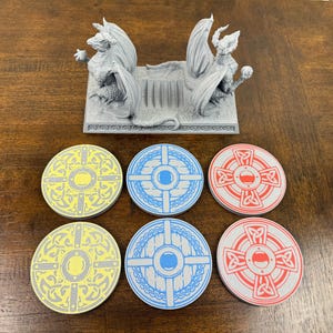 May include: Six round, decorative coasters with different designs.  Two coasters are yellow with a gray center and gray Celtic knot designs. Two coasters are blue with a gray center and gray Celtic knot designs. Two coasters are red with a gray center and gray Celtic knot designs.