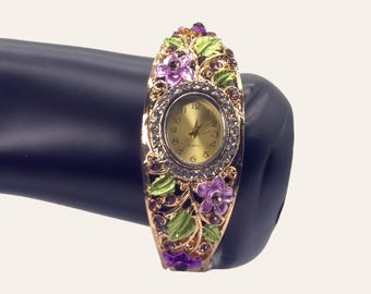 Reloj vintage de brazalete esmaltado con flores moradas y halo de diamantes de imitación en tono dorado.