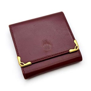 Porte-monnaie vintage Cartier en cuir bordeaux avec coins dorés et fermeture à pression
