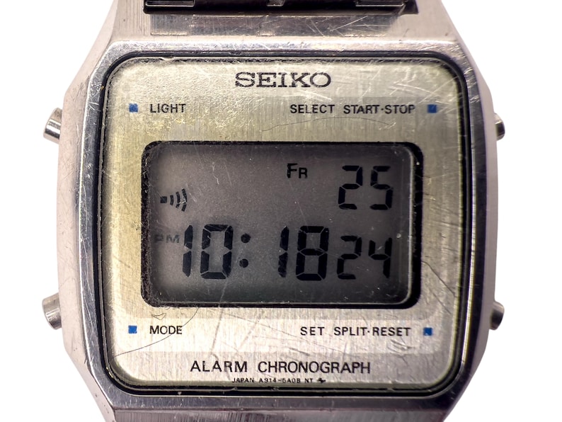 Puede incluir: Reloj digital Seiko vintage con caja plateada. La esfera muestra la hora 10:18 PM, la fecha 25 y el d&iacute;a FR. Funciones: luz, modo, alarma y cron&oacute;grafo.