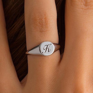 May include: A silver signet ring with the letter "K" engraved on the face.