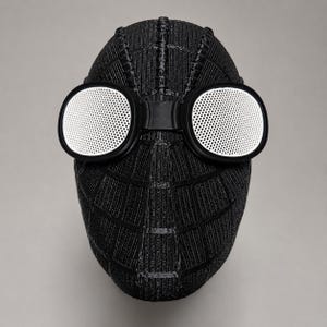 May include: A black Spider-Man mask with white mesh lenses. The mask has a textured surface with a web-like pattern. The lenses are round and set in black frames, connected by a bridge over the nose area. The mask is designed to cover the entire face.