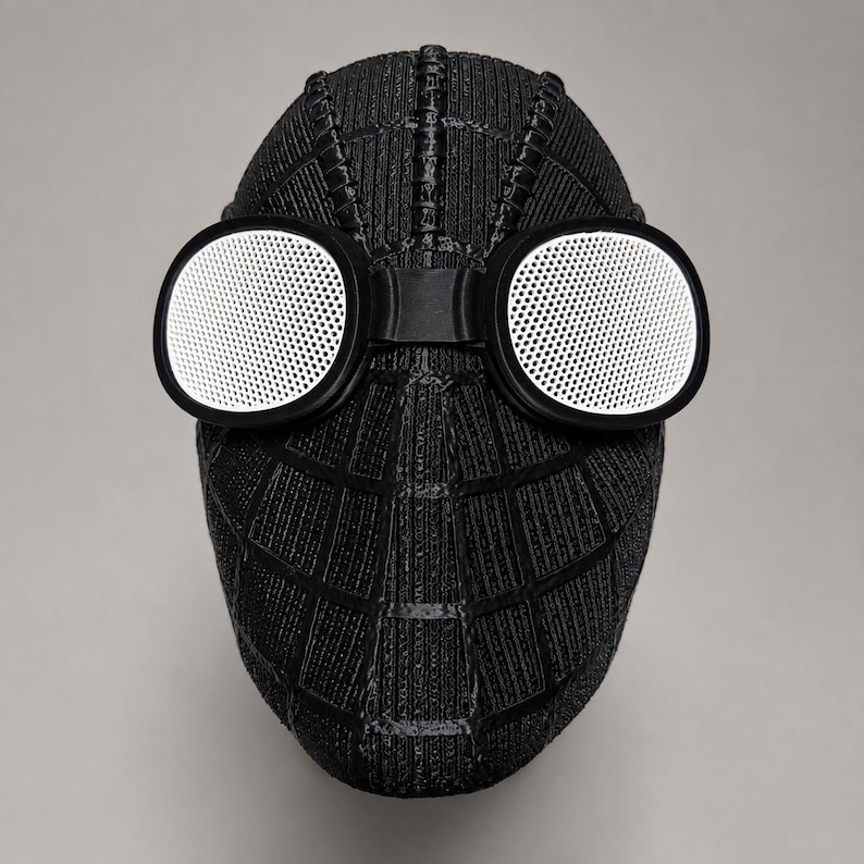 Op de afbeelding: Een zwart Spider-Man-masker met witte mesh-lenzen. Het masker heeft een textuur met een webpatroon. De ronde lenzen zitten in zwarte frames, verbonden door een brug over de neus. Het masker is ontworpen om het hele gezicht te bedekken.