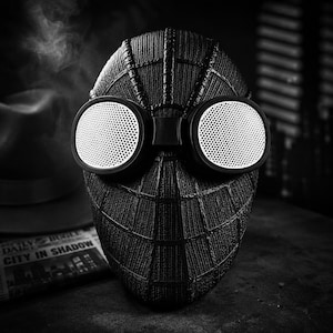 Op de afbeelding: Zwart-wit Spider-Man masker met grote, ronde witte lenzen. Het masker heeft een textuur, webachtig patroon en een donkere, matte afwerking. De lenzen zijn omgeven door een zwart frame. Dit is een cosplay-artikel.