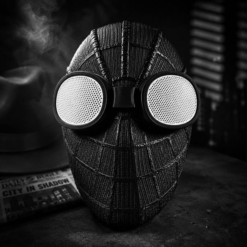 Op de afbeelding: Zwart-wit Spider-Man masker met grote, ronde witte lenzen. Het masker heeft een textuur, webachtig patroon en een donkere, matte afwerking. De lenzen zijn omgeven door een zwart frame. Dit is een cosplay-artikel.