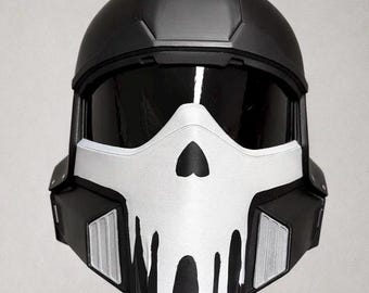 May include: A black and white helmet featuring a skull design on the face. The helmet has a visor and is likely for cosplay or costume use. The skull design is white with black accents, and the helmet is made of a hard material.