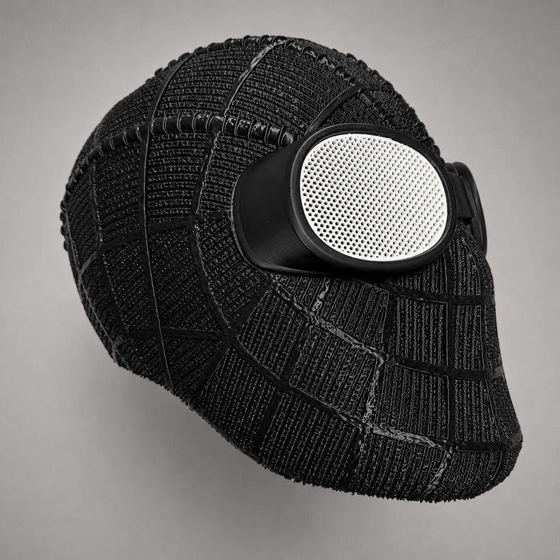 Op de afbeelding: Zwart Spider-Man-masker met een textuur, webachtig detail. Het masker heeft witte mesh ooglenzen in zwarte monturen. Het ontwerp is strak en modern, met gedetailleerde oppervlaktestructuur.