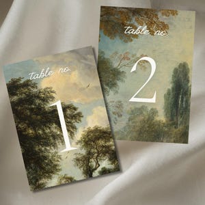 Może przedstawiać: Dwie karty z numerem stołu z tłem malowanego krajobrazu. Pierwsza karta ma numer "1" i tekst "table no." Druga karta ma numer "2" i tekst "table no."