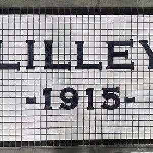 以下が含まれることがあります： 白黒のモザイクタイルの看板で、「LILLEY -1915-」の文字が書かれています。看板は白地に黒文字で、「MOSAIC LETTERING」の文字が左下の隅にあります。