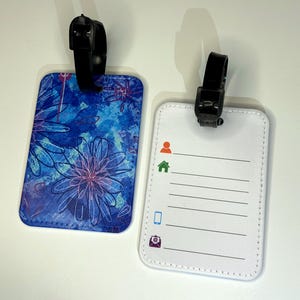 Bagagelabel met riem om aan de koffers en handbagage te bevestigen. Blossoming Collection bloemenprint, blauw. Voorzien van artwork van DAHLO.