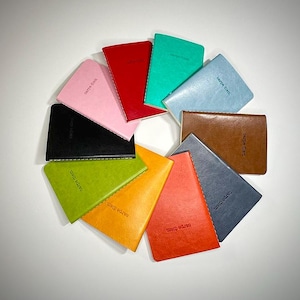 May include: A collection of colorful notebooks arranged in a circular pattern. The notebooks are in various colors, including pink, red, green, blue, brown, and black. Each notebook has the words "carpe diem" printed on the cover.