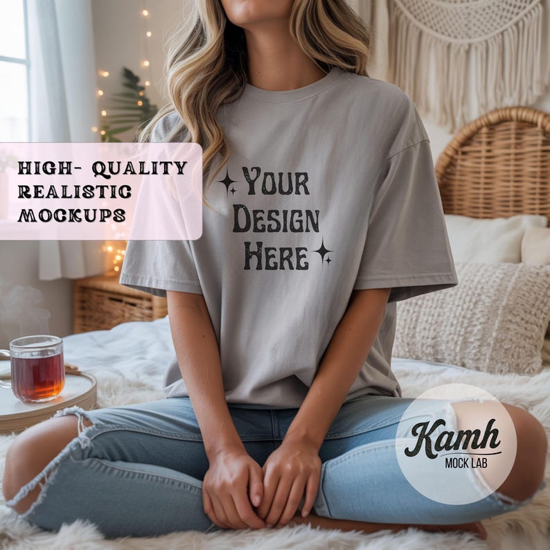 May include: A light gray t-shirt with the text "YOUR DESIGN HERE" in black. The shirt is part of a mockup, with the words "HIGH-QUALITY REALISTIC MOCKUPS" in a pink rectangle. The model is wearing blue jeans.