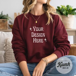 May include: A maroon sweatshirt with the text "Your Design Here" in a white, vintage-style font. The sweatshirt is long-sleeved and has a crew neck. The image is a mockup, suggesting the design can be customized.