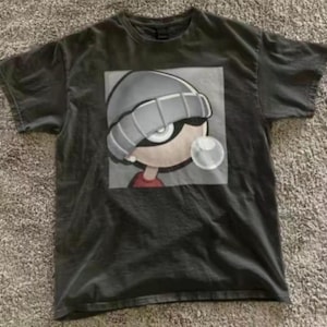 May include: Dark gray t-shirt featuring a cartoon character with a gray beanie, large eyes, and a bubble of gum. The character is set against a gray background. The shirt is made of a soft material.