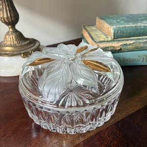Peut inclure: Un petit plat à bijoux en verre transparent avec un couvercle floral givré et des accents dorés. Le plat présente un motif détaillé et texturé. Décoratif et vintage.