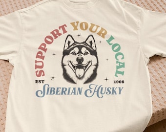 May include: Off-white t-shirt featuring a Siberian Husky dog graphic. The text "SUPPORT YOUR LOCAL" arches above the dog, with "SIBERIAN HUSKY" below. The year "1908" is also printed on the shirt.