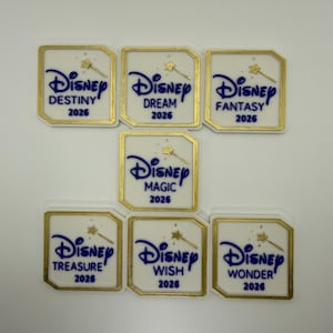 May include: Seven white and gold-framed Disney-themed rectangular stickers. Each sticker features the Disney logo in blue, a gold wand, and a ship name with the year 2026. The names include Destiny, Dream, Fantasy, Magic, Treasure, Wish, and Wonder.