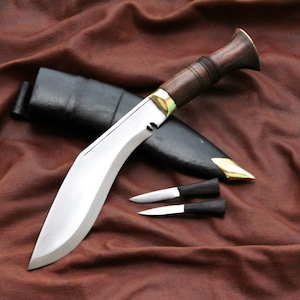 May include: A large, curved blade knife with a wooden handle and a black sheath. Two smaller knives are also present. The blade is silver, and the handle is dark brown. The sheath is black with gold accents.