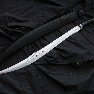 May include: A curved, silver sword with a black handle and sheath. The blade features circular cutouts. The sword rests on a black surface.