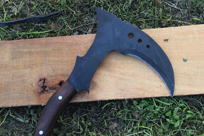 May include: A black curved knife with a wooden handle. The knife has a serrated edge and several holes in the blade.
